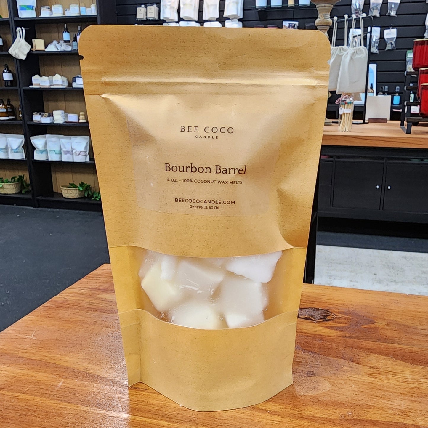 Bee & Coco bourbon barrel-aged white chocolate truffles in a brown paper bag on a wooden surface.