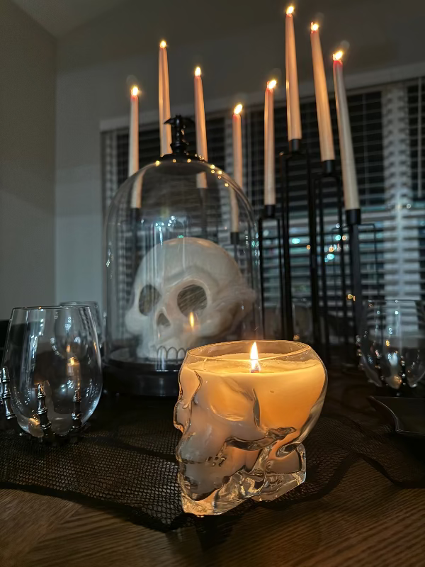Skull-shaped candle holders with lit candles on a table.