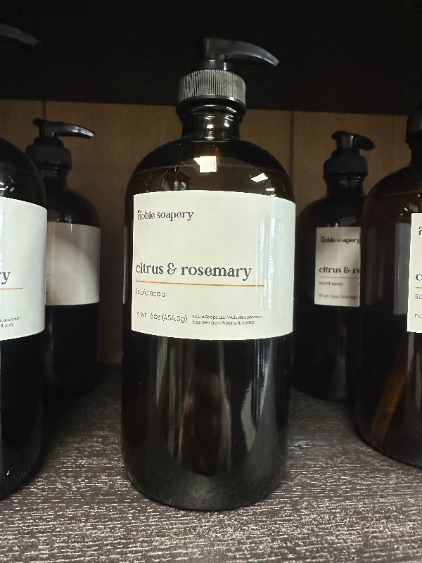 A dark amber glass bottle with a pump dispenser, labeled as 'citrus & rosemary' liquid soap.