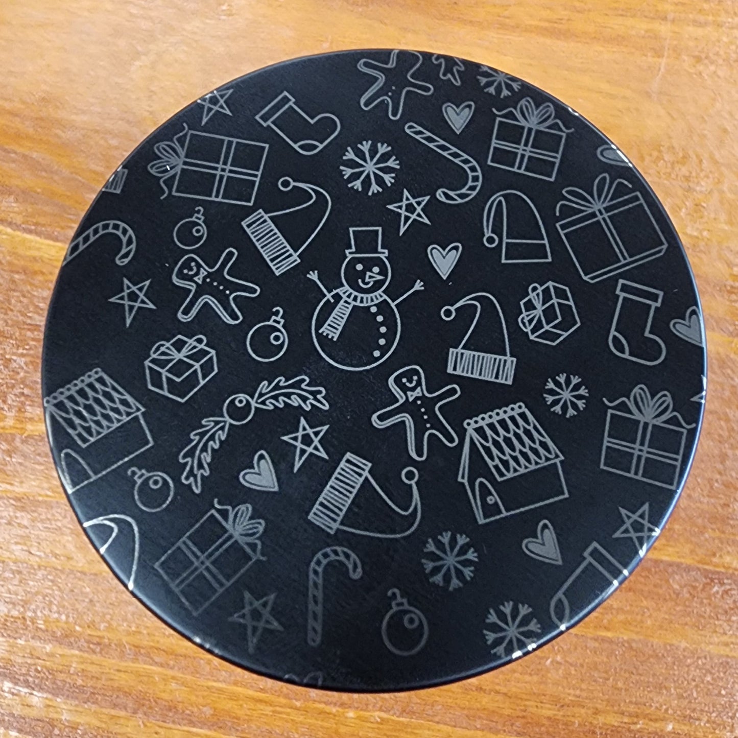 Laser engraved candle lid detail with cute winter-themed design on a wooden surface
