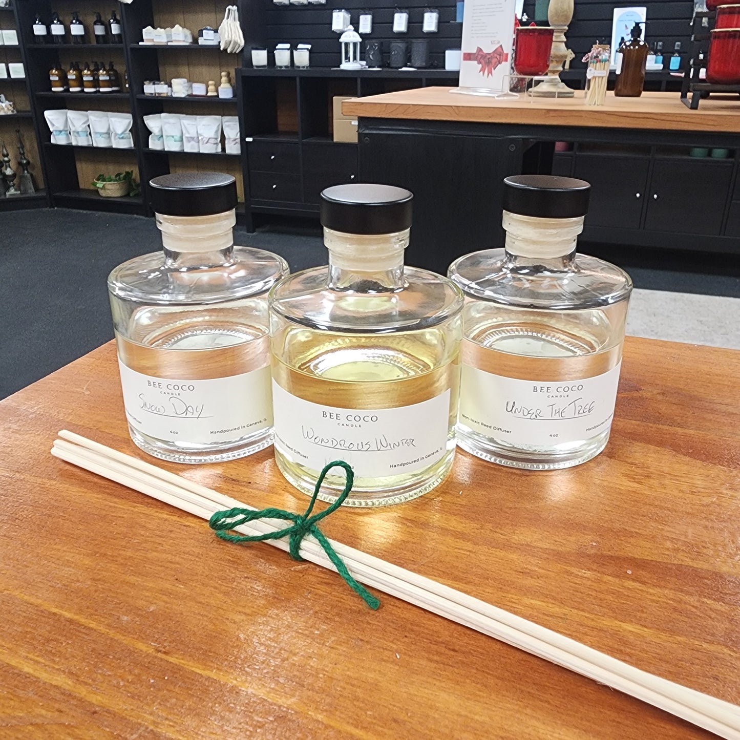 Three reed diffusers on a wooden surface with a blurred background
