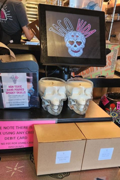 Two clear skull-shaped candles on a counter with a digital display showing a colorful design.