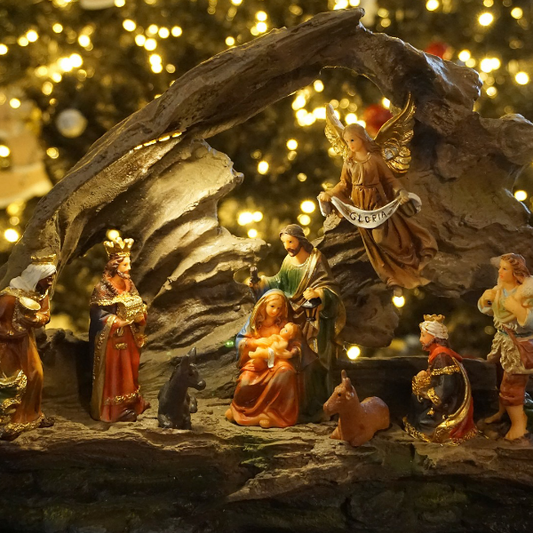 A Christmas-themed wax melt with a nativity scene featuring figures of Mary, Joseph, and baby Jesus, set against a backdrop of a tree decorated with lights.