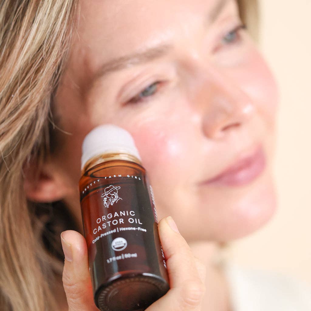 Person holding a bottle of organic castor oil close to their face