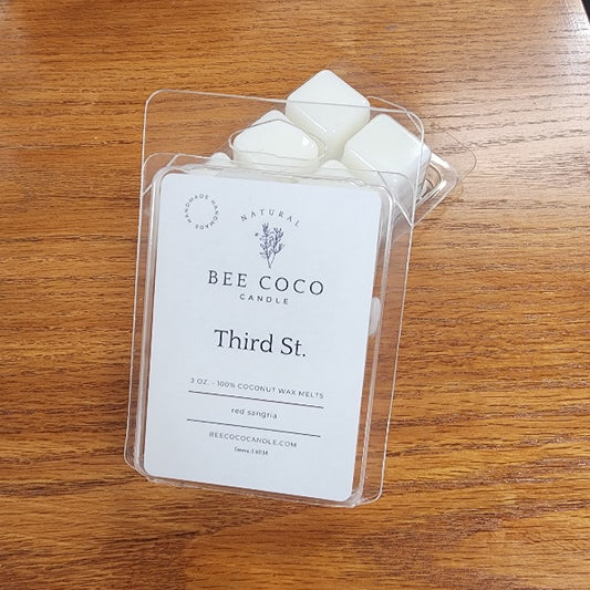 Bee Coco Candle packaging with three wax melts on a wooden surface