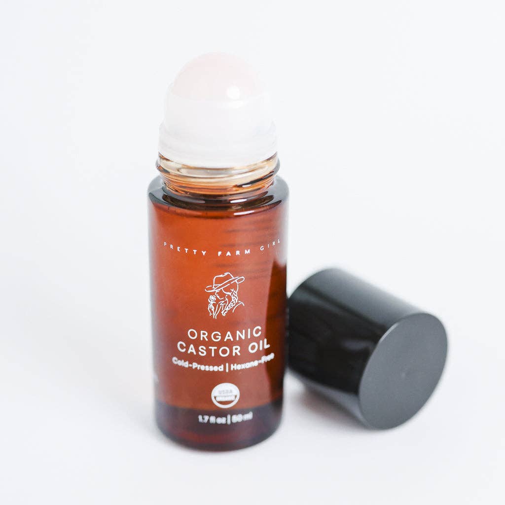 Roll-on bottle of organic castor oil with a white cap on a light gray background