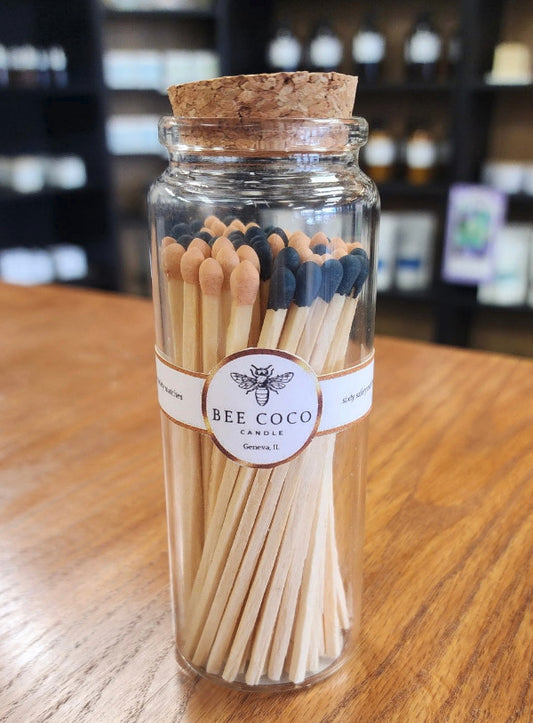 Jar of matches with a cork lid and 'Bee Coco' label on a wooden surface.
