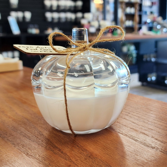 Glass candle with wick tied with twine on a wooden surface, blurred background