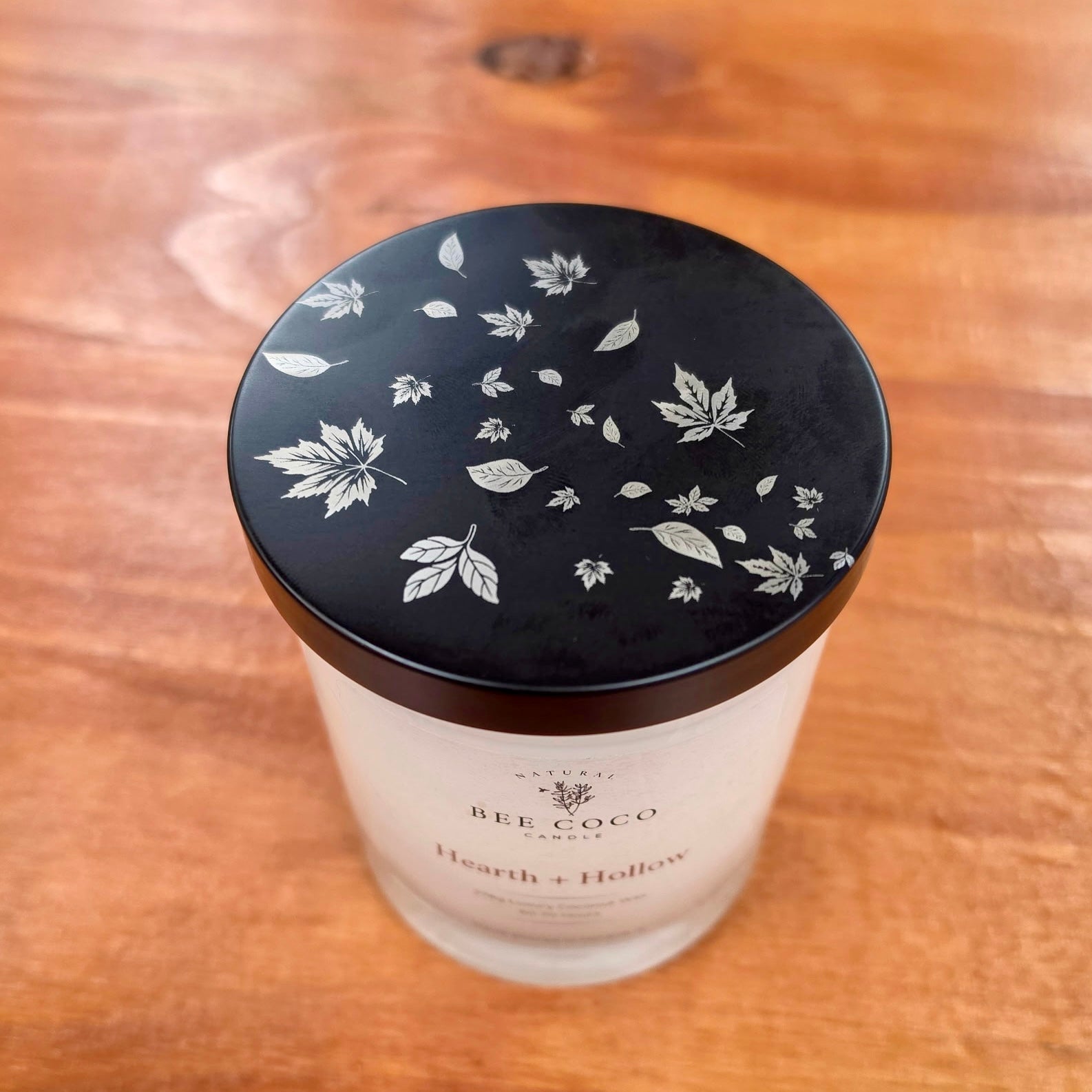 Top of Bee Coco Candle Hearth + Hollow candle showing fall engraved with blowing fall leaves.