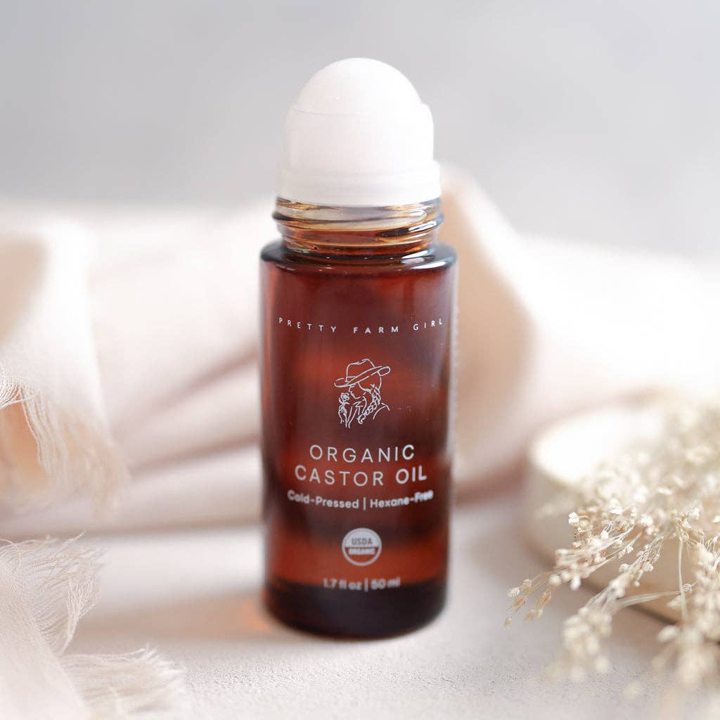 Roll-on bottle of organic castor oil with a white cap on a light background