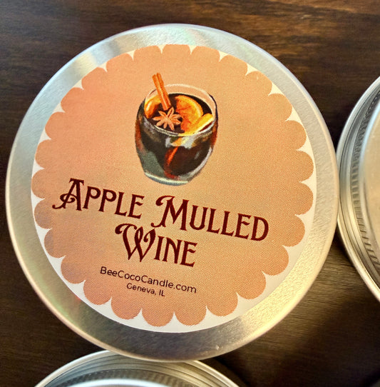 Tin of Apple Mulled Wine candle with a label on a wooden surface
