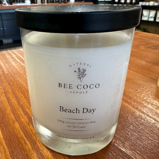 Bee Coco Beach Day candle on a wooden surface