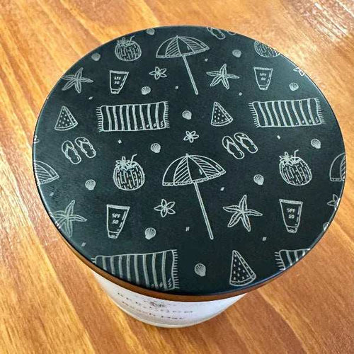 Black lid with white beach patterns on a wooden surface