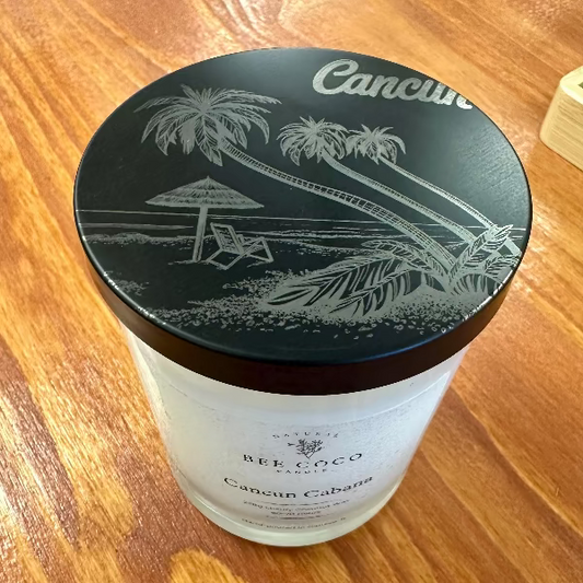 Candle jar with black lid featuring palm tree design on a wooden surface