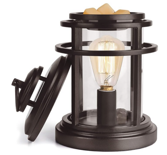 An electric wax warmer with a clear container, a black base, and an illuminated bulb inside, sitting on a white background.