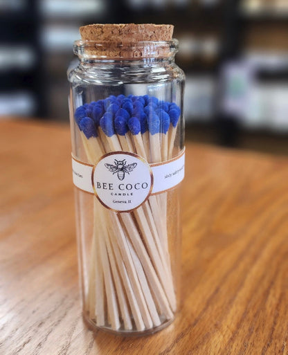 Jar of matches with blue tips and a visible label on a wooden surface