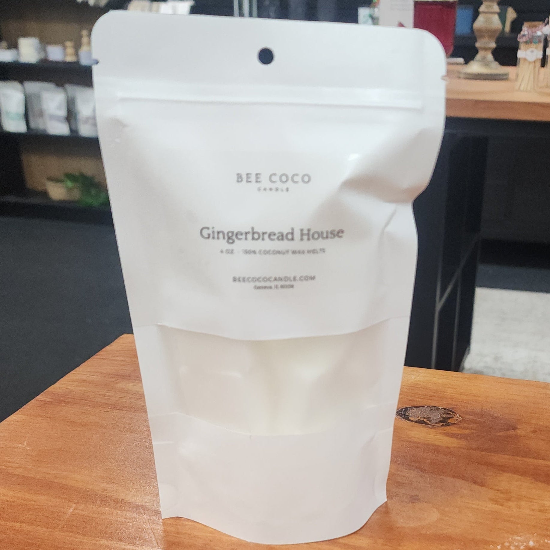 White packaging of 'Bee Coco Gingerbread House' on a wooden surface with a blurred background