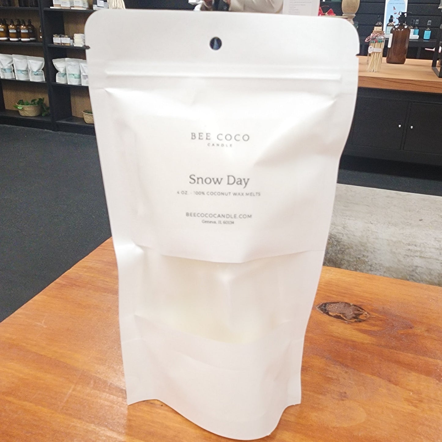 White packaging labeled 'Bee Coco Snow Day' on a wooden surface with a store interior in the background.