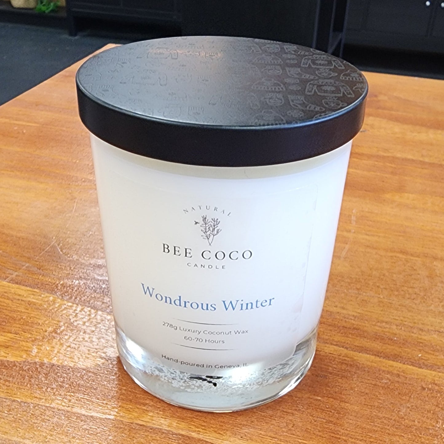 Candle with a black lid on a wooden surface