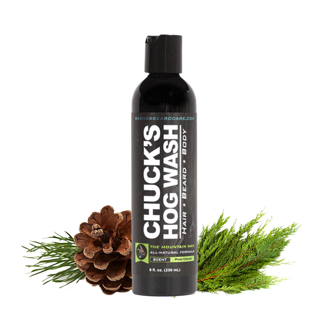 Bottle of Chuck's Hog Wash with a pine cone and greenery on a white background