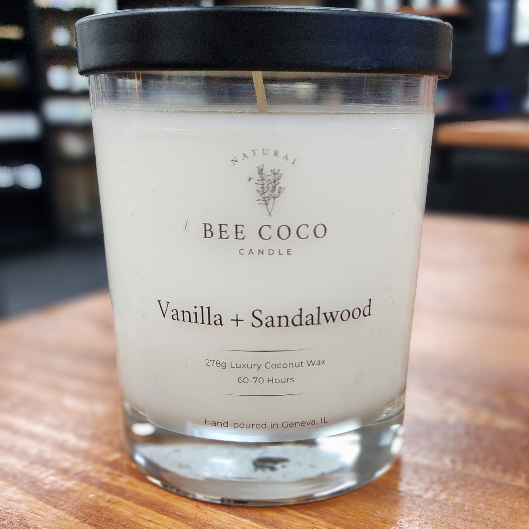 Candle labeled 'Bee + Coco' on a wooden surface